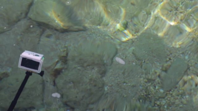 Man shooting video for home memories using action camera in waterproof case. Camera attached to black monopod. Real time full hd video footage.