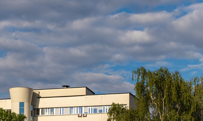 Fototapeta na wymiar tree crowns, office building and cloudy sky, Krakow