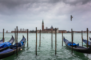 Fototapeta na wymiar San Giorgio Maggiore church and gondolas at cloudy day in Venice, Italy.