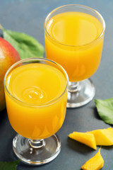 Two glasses with fresh mango juice on a blue background. Selective focus