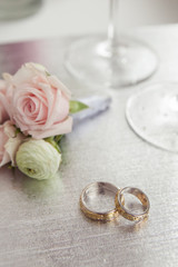 Obraz na płótnie Canvas Wedding rings with flowers and glasses