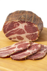 Hickory smoked pork shoulder - stuffed in net and sliced on cutting board