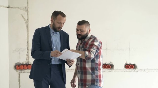 Two men discuss plan of the new apartment
