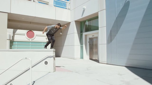 Young man doing parkour outside free running in urban city doing extreme front flip off wall