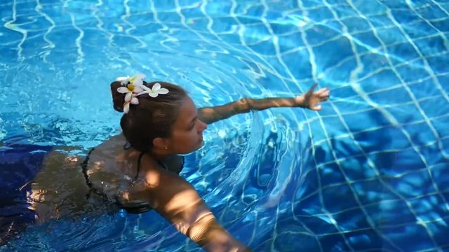 Girl with flowers in her hair floating in the blue swimming pool. view from above. slow motion, HD, 1920x1080
