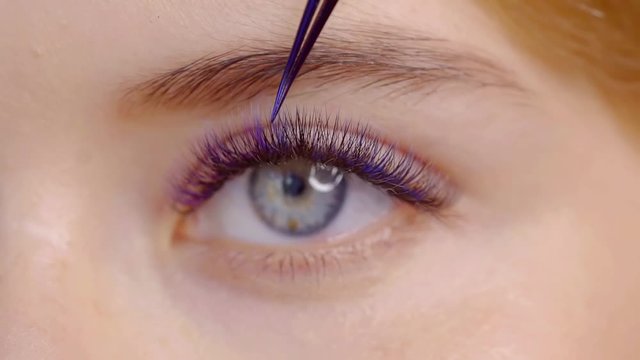 Close-up of the female eye . demonstration of volumetric extension with multi-colored eyelashes