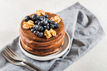 Stack of homemade chocolate pancakes with blueberries and chocol
