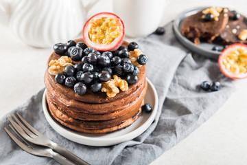 Stack of homemade chocolate pancakes with blueberries and chocol