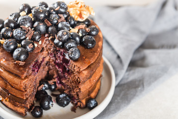 Stack of homemade chocolate pancakes with blueberries and chocol