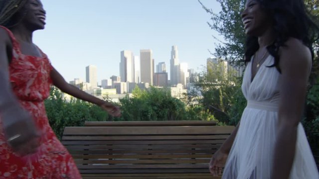 Slow motion of two black women hugging with Downtown Los Angeles in the back