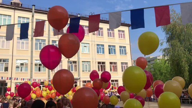 Many balloon and flag in school, children happy, tied to a string floats in blue sky. Many colorful balloons flying in the air. Celebration and birthday concept. Holiday day of knowledge, September 1.