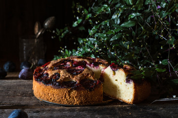 Homemade plum pie on the old wooden background. Vintage spoon. Still life of food. plum tart. Autumn harvest. Old fashion cuisine. Portion of pie. Plum bakery. Rustic open pie.