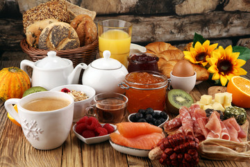 breakfast on table with bread buns, croissants, coffe and juice.