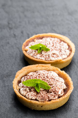 Mini  banoffee pie tarts isolated on black stone background