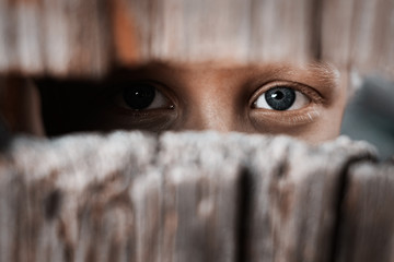 Boy looks through the gap in the fence. The concept of voyeurism, curiosity, Stalker, surveillance...