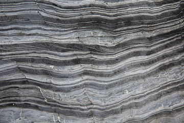 A textured background image of the layers of slate and marble that have been compressed together over millions of years in the cross section of a geological rock formation - Powered by Adobe