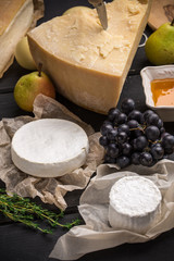 Parmesan and goat cheese with pears, grape and honey on dark wooden table