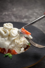 Whole tied Italian cheese burrata on small wooden plate served with fresh tomatoes and basil on dark textured background © Eduard Zhukov