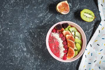 Raspberries smoothie bowl with figs, kiwi and coconut on concrete background