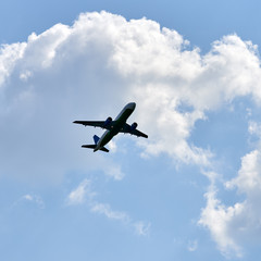 Fototapeta na wymiar Passenger airplane flying against white clouds and blue sky.