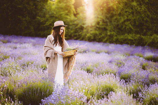 Young Woman Holding Basket Of Lavender Flowers In Field