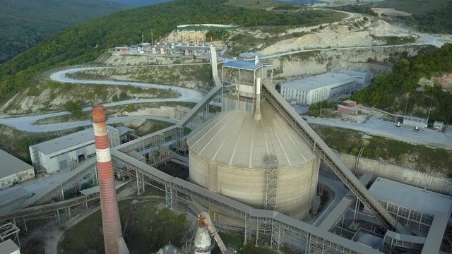 Aerial view of cement factory, large industrial building in the mountains. Concept of cisterns, pipes, metal structures, concrete production. Top view.