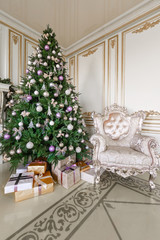 gifts at the Christmas tree. Christmas morning. classic luxurious apartments with a white fireplace, sofa, large windows and chandelier.