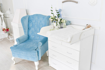Blue chair and changing table for infants. interior of a spacious children's room.