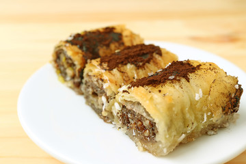 Closed up a place of three pieces of delicious Baklava sweets served on wooden table 