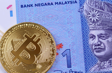 A blue one Malaysian ringgit banknote with a golden bitcoin