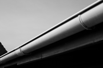 A black and white image of a plastic rain gutter.  This image can also be used to represent house maintenance. 