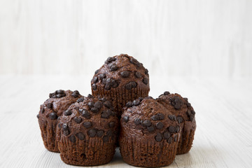 Chocolate cupcakes on white wooden background, side view. Close-up.