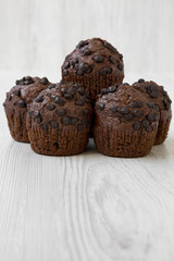 Chocolate muffins on white wooden background, side view. Close-up.