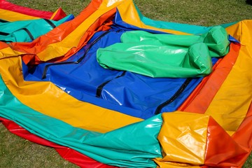 A colorful deflated jumping castle on a green lawn. This image can be used to represent the concept...