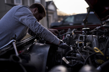 Man repairing car's engine outdoors