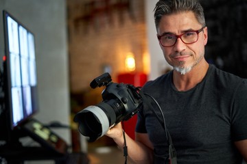 Older man holding photo camera smiling
