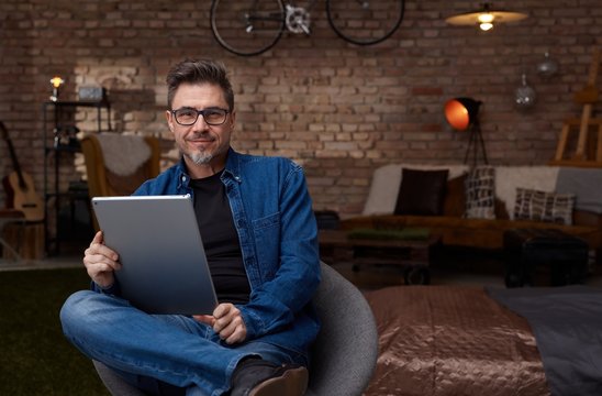 Happy confident man in glasses using tablet