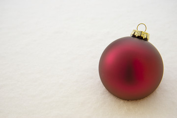Red christmas ball on white snow background