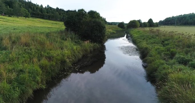 Close up river scene. Camera follows river farm fields asides and above water during summer sunny evening at Espoo. Finland. Scandinavia.