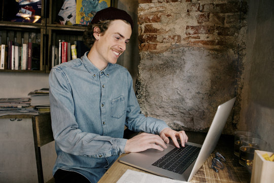 Happy man using laptop computer on table while sitting at home
