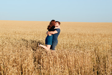 Naklejka na ściany i meble young loving couple in nature in summer on a background of field with oats