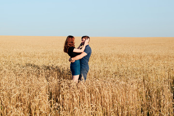 Naklejka na ściany i meble young loving couple in nature in summer on a background of field with oats