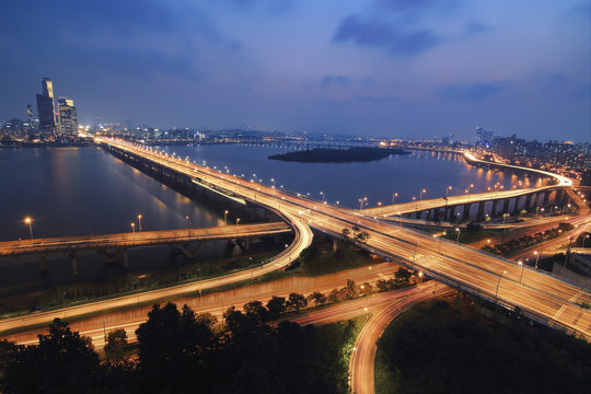 Aerial view of illuminated light trails on Mapo Bridge over Han River against blue sky at night
