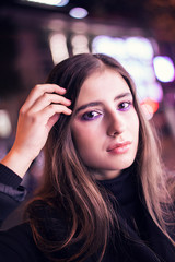 Portrait of woman with beautiful makeup, purple color. Night on the street, beautiful bokeh.