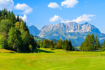 Green golf course area against mountains background on sunny summer day, Kitzbuhel, Tyrol, Austria