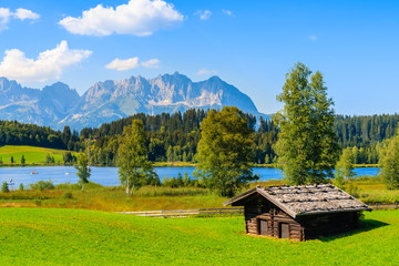 Wooden hut on green meadow against Alps mountains near Schwarzsee lake on sunny beautiful summer...