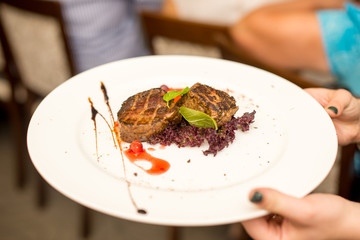 fried beef steaks with spices, plate in hand