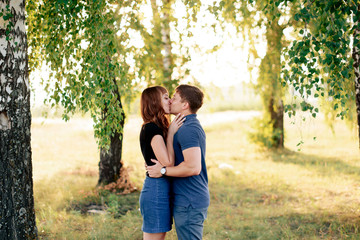 Fototapeta premium young loving couple in nature in summer on a background of green leaves