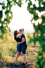 young loving couple in nature in summer on a background of green leaves