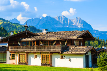 Typical alpine house on green meadow in Reith bei Kitzbuhel village in Alps mountains summer landscape on sunny day, Tirol, Austria